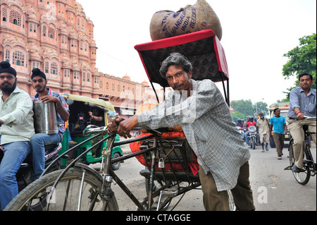 Mann schob geladen Rikscha vor Palast der Winde, Palast der Winde, Hawa Mahal, Jaipur, Rajasthan, Indien Stockfoto