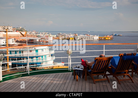 Gast auf dem Deck des Kreuzfahrtschiffes MS Deutschland der Reederei Peter Deilmann, mit Blick auf Boote von Amazonas, Manaus, Amazonas, Brasilien, Stockfoto