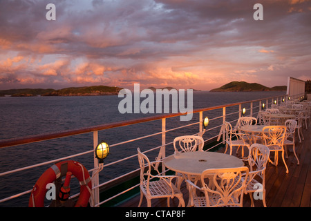 Tische und Stühle auf dem Deck des Kreuzfahrtschiffes MS Deutschland, Reederei Peter Deilmann mit Wolken bei Sonnenuntergang, Cabo Frio, Rio de Janeiro Stockfoto