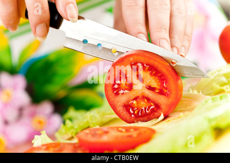 Frauenhand Tomate hinter frisches Gemüse schneiden. Stockfoto