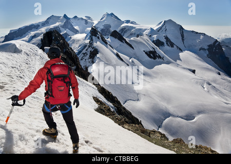 Bergsteiger geht auf verschneiten Grat Breithorn genau auf schweizerisch-italienischen Grenze IIn Hintergrund Hauptgipfel Monte Rosa-Massiv Stockfoto