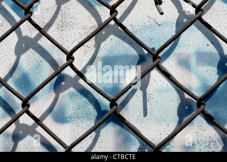 Close-up auf ein Maschendrahtzaun vor einem weißen Hintergrund mit blauen Tropfen Sprühfarbe Stockfoto