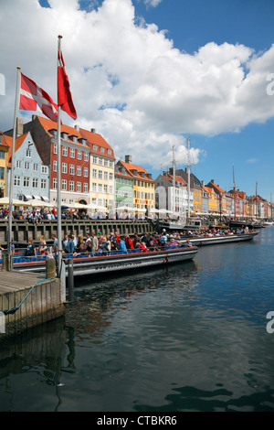 Die bunten und belebten Nyhavn Kai und schwere Kanal Kreuzfahrt Bootsverkehr an einem sonnigen Sommertag mit vielen Touristen Stockfoto