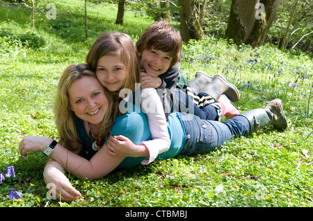 Porträt einer Mutter, die auf ihrem Bauch liegt und ihre beiden Kinder auf dem Bauch liegen Stockfoto