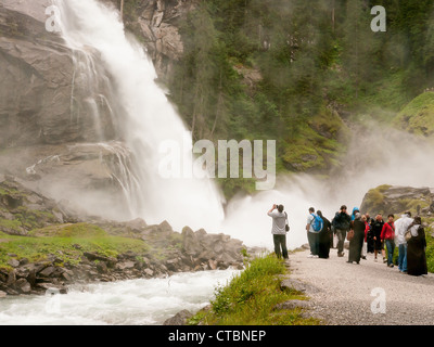 Touristen in der Gischt am Fuße der Krimmler Wasserfälle in Österreich, die höchste in Europa Stockfoto