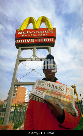 Deon Ncube verkauft Zeuge Zeitung vor McDonalds goldenen Bögen, das er verdient R30 pro Arbeitstag 6 bin 11:00, was er will get Stockfoto