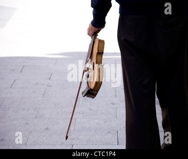 ein Mann geht durch die Straßen von Madrid trägt eine Geige Stockfoto