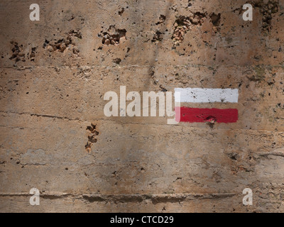 Routenmarker für GR92 Küstenweg auf eine Betonmauer im Sonnenlicht Stockfoto