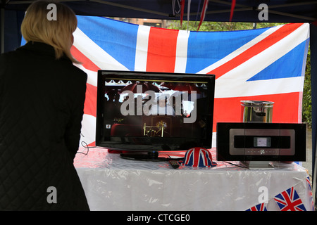 Frau vor dem Königin Elizabeth II im Fernsehen am Straßenfest unter Festzelt während der Queens Diamond Jubilee Surrey Englands Stockfoto