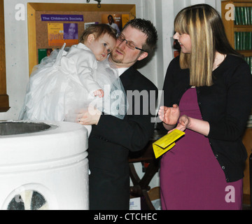 Eltern mit Baby Girl bei der Taufe an Str. Marys Kirche Caterham auf dem Hügel Surrey England Stockfoto