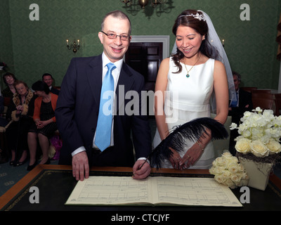 Braut und Bräutigam Unterzeichnung das Register mit Feder während der Hochzeit im Standesamt, Merton In Morden Park House England Stockfoto