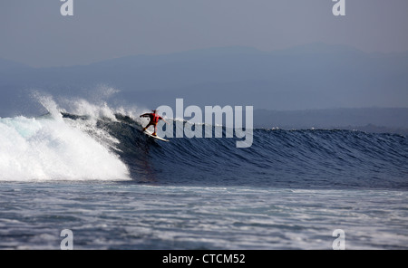 Bärtiger Mann Surfen eine Welle rot Superhelden-Kostüm tragen. Stockfoto