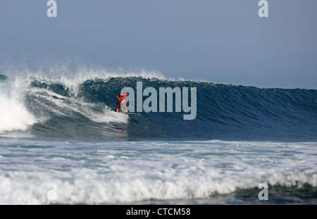 Bärtiger Mann Surfen eine Welle rot Superhelden-Kostüm tragen. Stockfoto