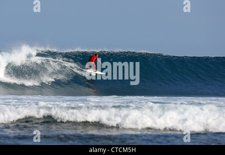 Bärtiger Mann Surfen eine Welle rot Superhelden-Kostüm tragen. Stockfoto