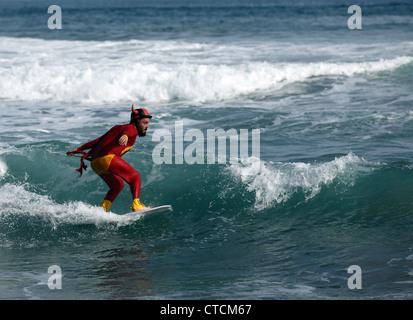 Bärtiger Mann Surfen eine Welle rot Superhelden-Kostüm tragen. Stockfoto