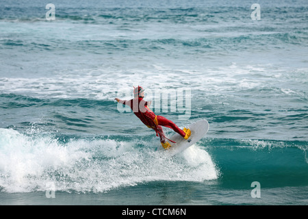 Bärtiger Mann Surfen eine Welle rot Superhelden-Kostüm tragen. Stockfoto