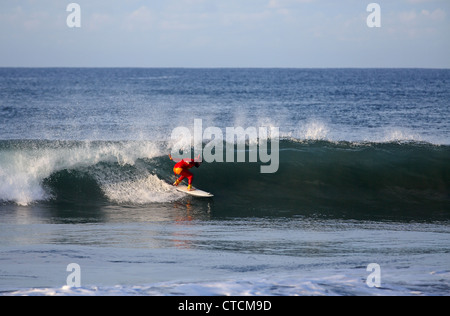 Bärtiger Mann Surfen eine Welle rot Superhelden-Kostüm tragen. Stockfoto