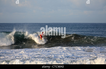 Bärtiger Mann Surfen eine Welle rot Superhelden-Kostüm tragen. Stockfoto