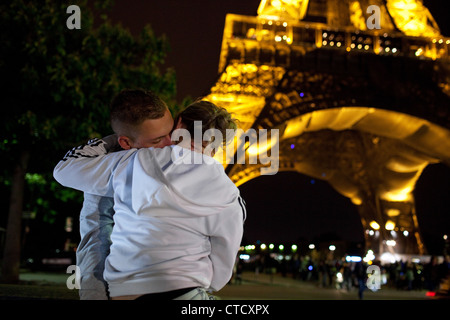 Ein paar Küsse und umfasst in der Nacht vom Seineufer mit dem Eiffelturm in Paris, Frankreich im Hintergrund. Stockfoto