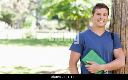 Porträt eines lächelnden bemuskelt Studenten halten ein Lehrbuch Stockfoto