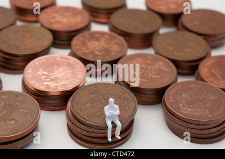 Besorgt Figur sitzt auf Stapel von Kupfer zwei Pence-Stücke Stockfoto