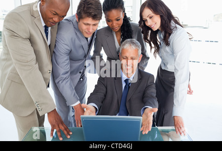 Ältere Manager am Schreibtisch umgeben von seinem schweren team Stockfoto