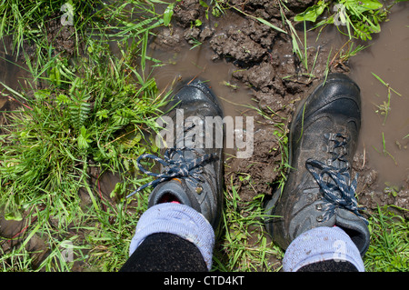 Eine Frau Wanderschuhe durchnässter da sie auf aufgeweichten Boden in Port Wiesen, Oxford, UK steht Stockfoto