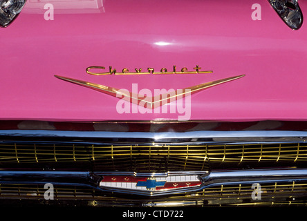 Eine Nahaufnahme der rosa Automobil-Haube (Mütze) mit den Insignien und Markenname eines amerikanischen Oldtimers, das Modell von 1957 Chevrolet (Chevy) Bel Air. Stockfoto