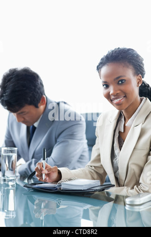 Young executive Frau arbeiten und einen ernsthaften Kollegen weiter lächelnd ihr Stockfoto