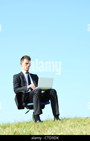 Business-Mann mit Laptop auf Stuhl Stockfoto