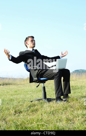 Business-Mann mit Laptop auf Stuhl Stockfoto