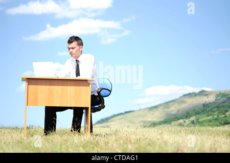 Geschäftsmann am Schalter in der Natur Stockfoto
