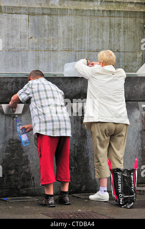 Pilger füllen Flaschen mit Heilwasser im Frühjahr die Wallfahrtskirche unserer lieben Frau von Lourdes, Pyrenäen, Frankreich Stockfoto