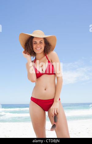 Frau in Bademode hält ihre Sonnenbrille Stockfoto