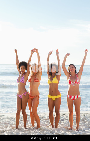 Vier Freunde lächelnd, während Sie ihre Arme an einem Strand Stockfoto
