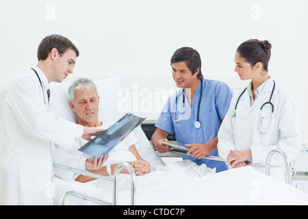 Arzt einen Röntgen-Scan zu einem Patienten zeigt, während von einem Arzt und einer Krankenschwester beobachtet Stockfoto