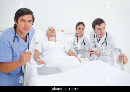 Krankenschwester und zwei Ärzte drängen einem Krankenhausbett Stockfoto