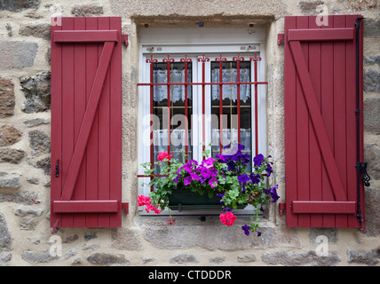 Nahaufnahme eines hübschen Fensters mit roten Holzfenstern und Blumen in Dinan, Bretagne, Frankreich Stockfoto