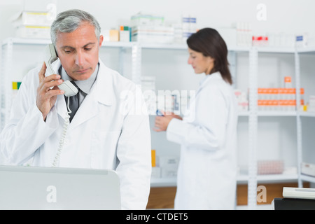 Apotheker über die Telefon-Stellung in einer Apotheke mit einem anderen Apotheker Stockfoto