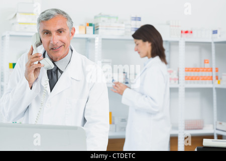 Apotheker auf dem Handy in einer Apotheke mit einem anderen Apotheker Stockfoto