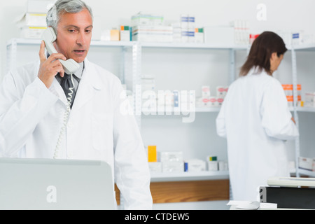 Mit einem Telefon in einer Apotheke mit einem anderen Apotheker Apotheker Stockfoto
