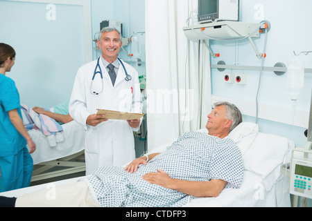 Lächelnde Arzt mit dem Patienten in einer Betten-Station Stockfoto