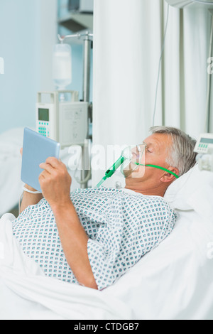 Älteren männlichen Patienten tragen eine Sauerstoffmaske beim Verwenden eines taktilen Tablets Stockfoto