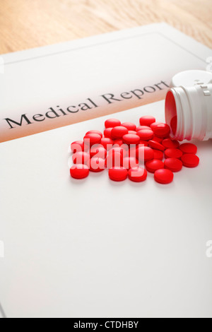 Ein medizinisches Gutachten auf einem hölzernen Tisch, eine weiße Pille Flasche verschütten rote Tabletten drauf. Stockfoto