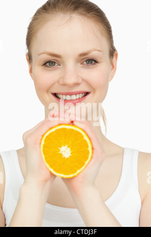 Lächelnde Frau, die eine Orange in ihren Händen hält Stockfoto