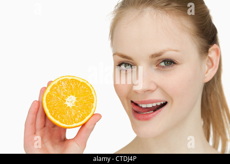 Frau mit einer Orange beim platzieren ihre Zunge über ihre Lippen Stockfoto