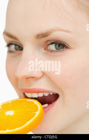 Nahaufnahme einer Frau eine Orangenscheibe in den Mund legen Stockfoto