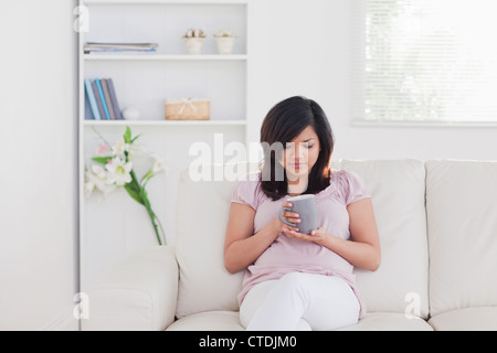 Frau, entspannend, wie sie auf einem Sofa sitzt Stockfoto