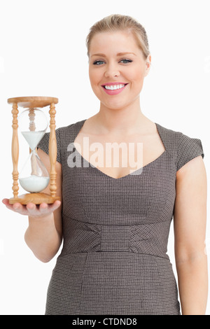 Halten Sie eine Sanduhr lächelnde Frau Stockfoto