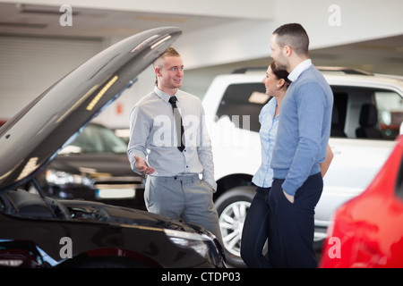 Paar steht vor einem offenen Automotor Stockfoto